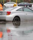A car swamped by floodwaters in Carribean Dr is cleared from the road. Photo / Michael Craig
