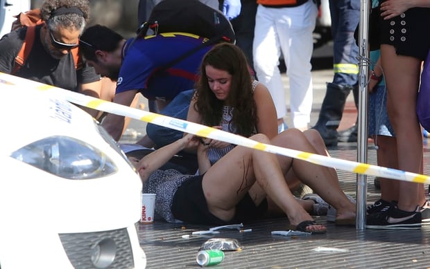 Injured people are treated in Barcelona after a white van jumped the sidewalk in the historic Las Ramblas district. Photo / AP