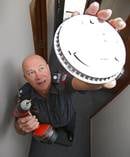Bay of Plenty coast area fire risk management officer Bill Rackham installs a smoke alarm. Photo / File