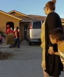 Neighbour Avery Sanchez, 6, peeks behinds his mother, Liza Tozier after dropping off his large 'Teddy' for the children who lived at the 'House of Horrors' in California. Photo / AP