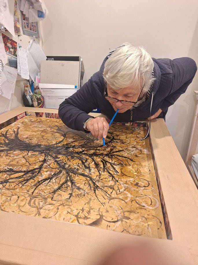 Elaine Williams blows paint through a straw while working on her creation for Artful Mind. Photo: Bronwyn Copeland.