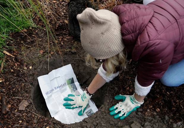 Student Delany Tarr from the Marjory Stoneman Douglas High School in Parkland, Florida, places a student newspaper article in the ground before she plants a tree.