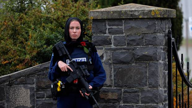 Police officer Michelle Evans stands guard with a rose and a hijab at the service for the burial of a victim of the Friday March 15 mosque shootings in Christchurch. Photo / AP