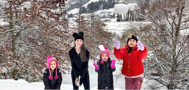 Liz Dotcom plays in the snow with three of Kim's children at the Dotcoms' new home near Queenstown on Thursday. Photo / Daisy Hudson