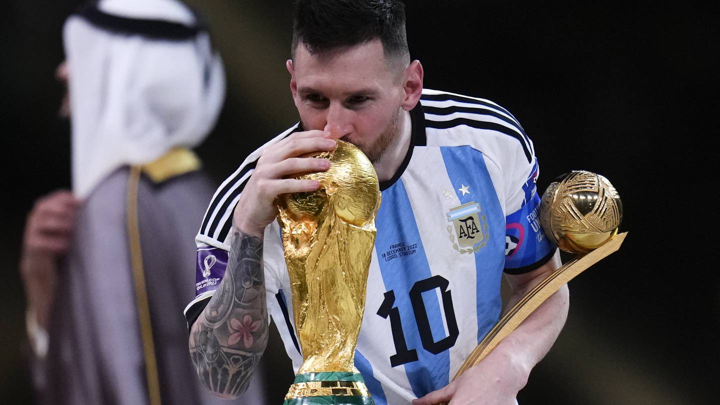 Argentina's Lionel Messi kisses the World Cup trophy as he holds the Golden Ball award for best player of the tournament. Photo / AP