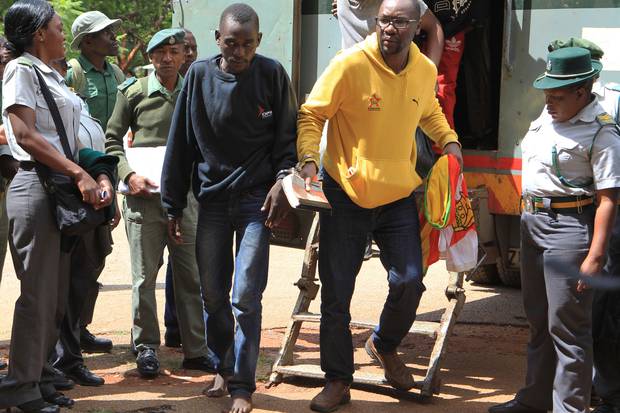 Pastor and activist Evan Mawarire, right, arrives handcuffed at the magistrates courts in Harare. Photo / AP