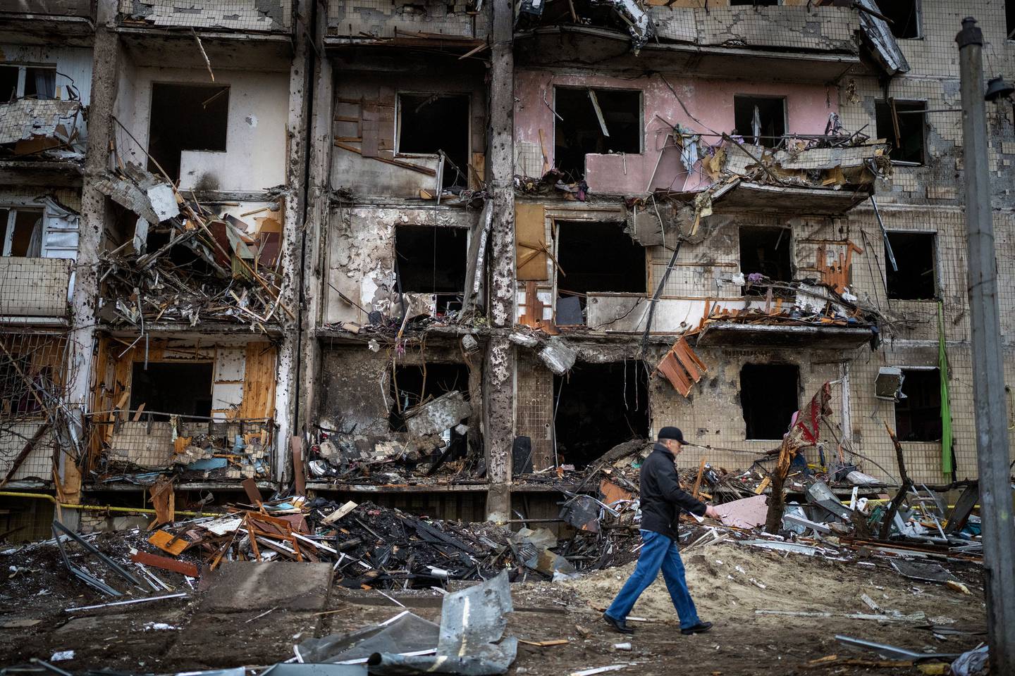 一名男子走过基辅市遭到火箭袭击后受损的建筑物。 照片/美联社