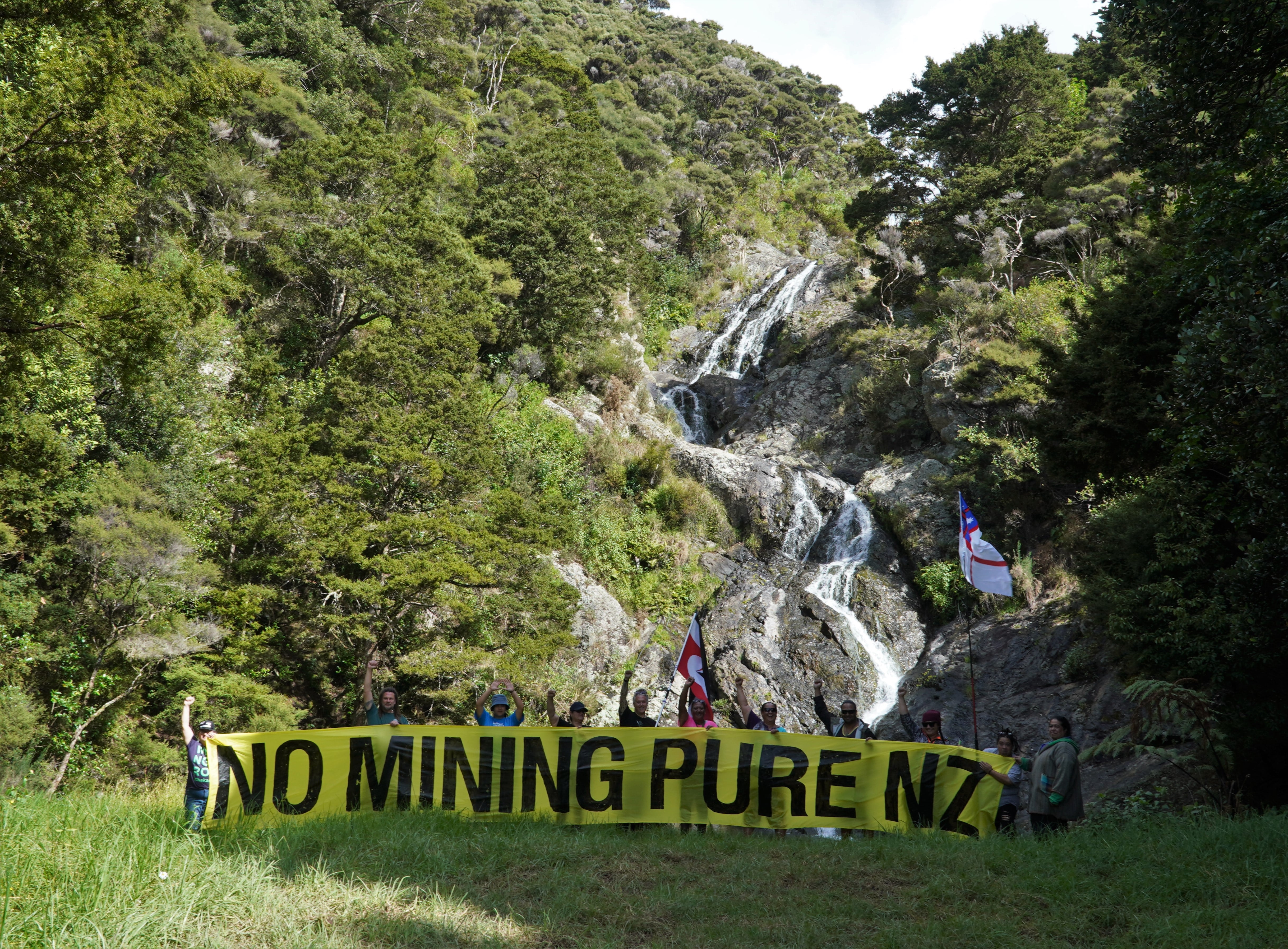 Protesters unfurl a banner at the foot of a waterfall near Te Ngaere, downstream from a conservation reserve where a mineral prospecting licence has been granted. Photo / Forest & Bird