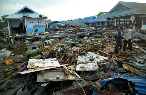 Indonesian men survey the damage following earthquakes and a tsunami in Palu, Central Sulawesi, Indonesia. Photo / AP
