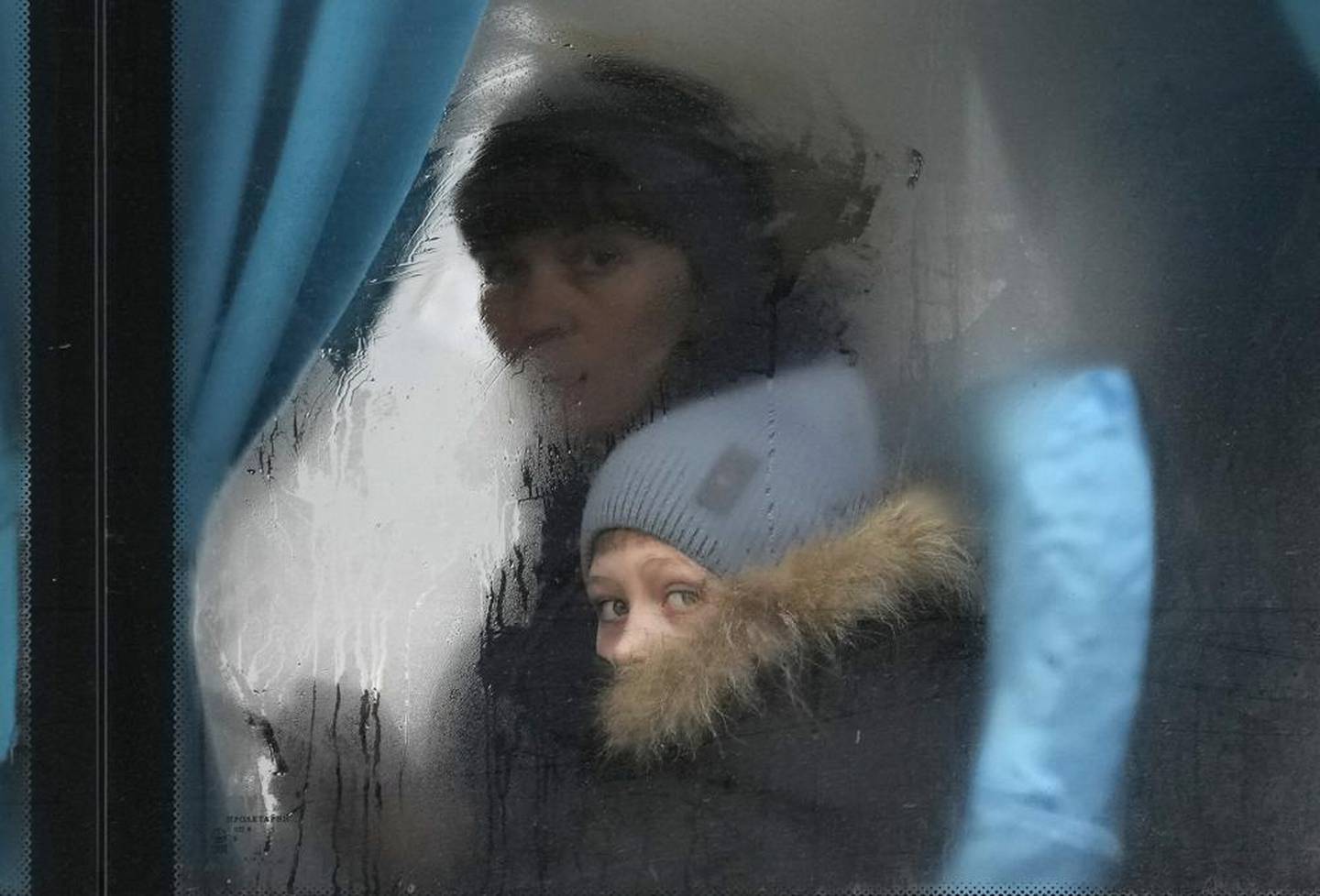 离开乌克兰东部卢甘斯克地区的西维尔顿涅茨克时，一名妇女和儿童从一辆公共汽车的窗外凝视。 照片/美联社
