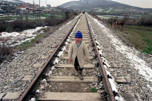 NjÃ« djalÃ« i vogÃ«l ecÃ«n gjurmÃ«t hekurudhore ndÃ«rsa familja e tij ikÃ«n nga fshatrat e tyre.  Foto / PÃ«rplas Goddard