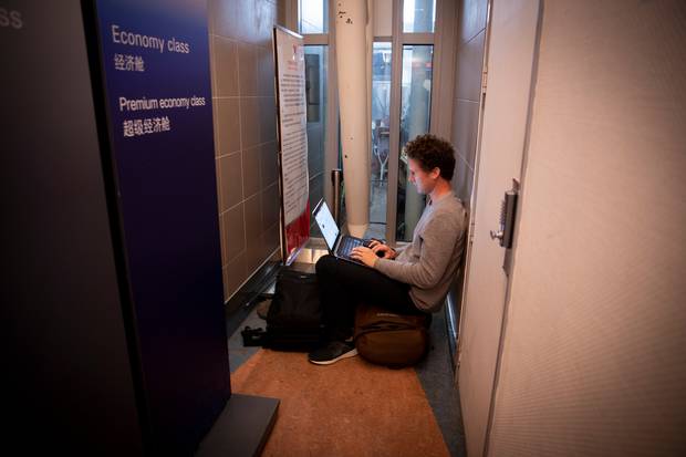 Myles Montgomery finds a place to keep his laptop charged while waiting for his flight check-in to open at Auckland International Airport. Photo / Dean Purcell