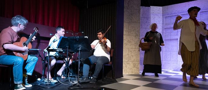 Musicians on stage (from left) Kelly McNamara plays guitar, musical director Matt Bodman and Nrusingha Rath on violin as actors arrive on the stage. Photo / Pete Luxford Photography