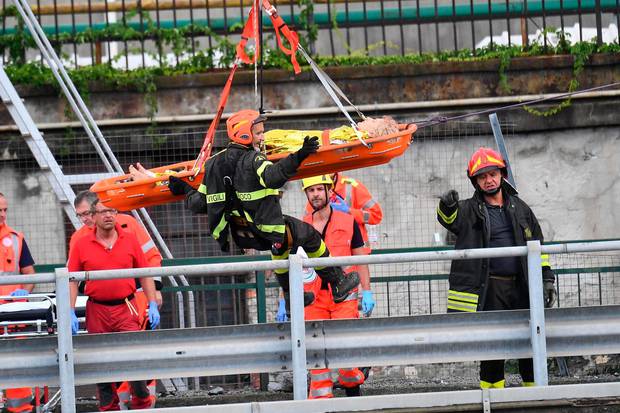 Rescuers recover an injured person after the Morandi highway bridge collapsed in Genoa, northern Italy. Photo / AP