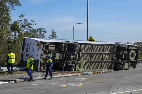 Police inspect underneath a bus that rolled onto its side near in the Hunter Valley. Photo / AP