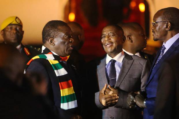 Zimbabwean President Emmerson Mnangagwa, left, arrives in Harare after cutting short his fund-raising trip in order to address the country's economic crisis and crackdown. Photo / AP