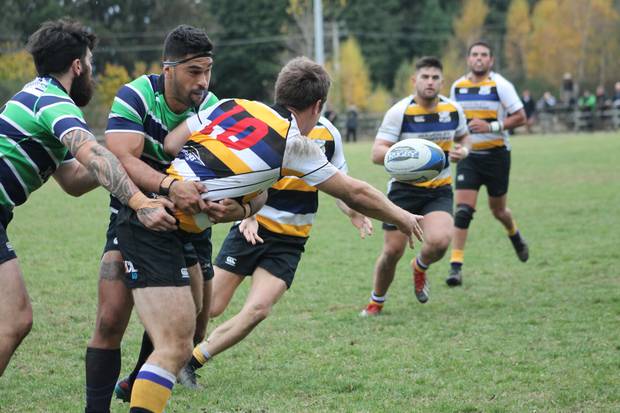 Ruapehu's Troy Brown holds his former midfield partner and current Border first-five Craig Clare, who still offloads at Rochfort Park.