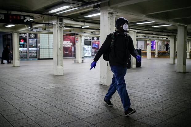A subway customer wears protective gloves and a face mask due to COVID-19 concerns while walking towards a train platform at Times Square. Photo / AP