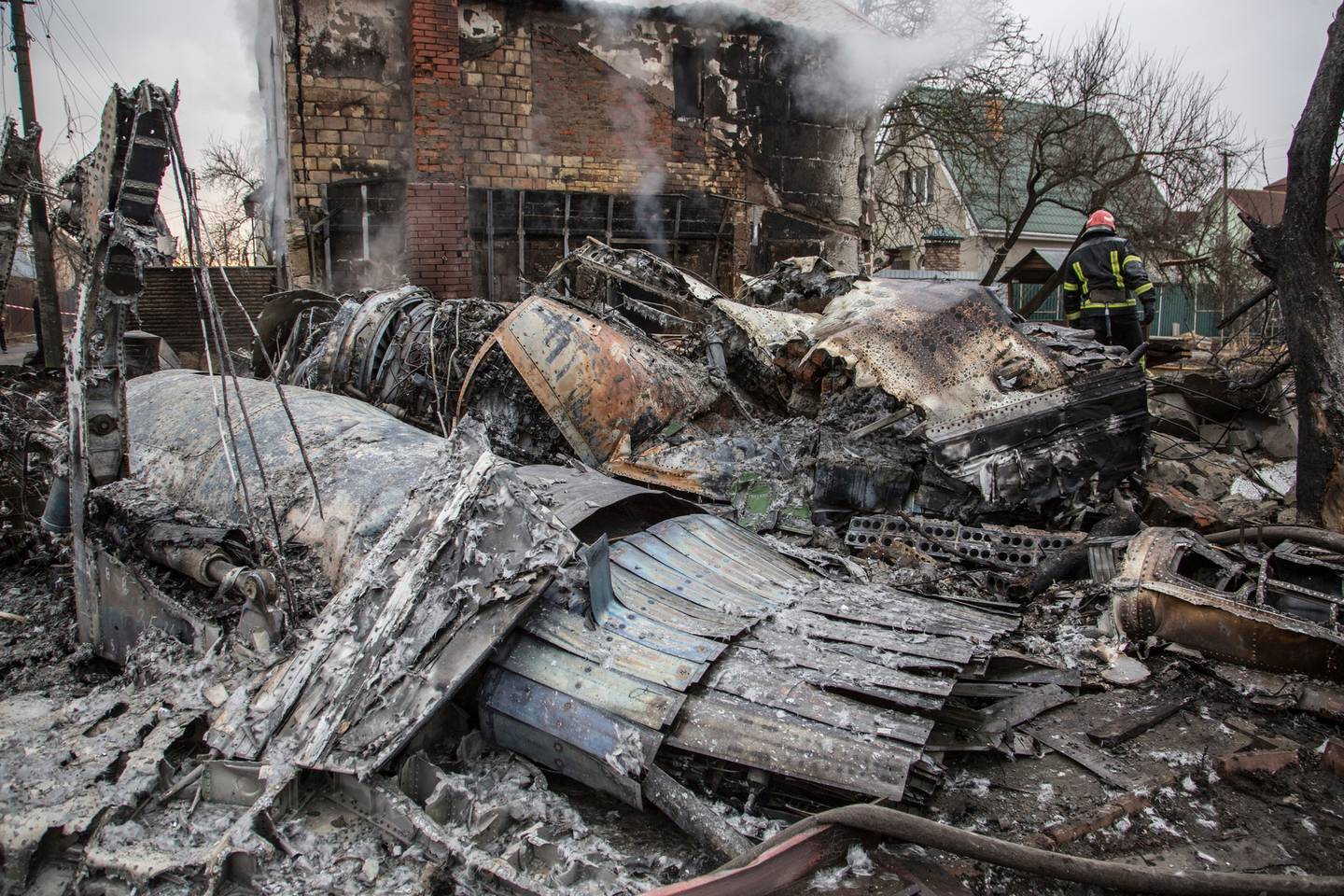 2 月 25 日，在乌克兰基辅，一名乌克兰消防员在一架被击落的飞机碎片之间行走。照片/美联社