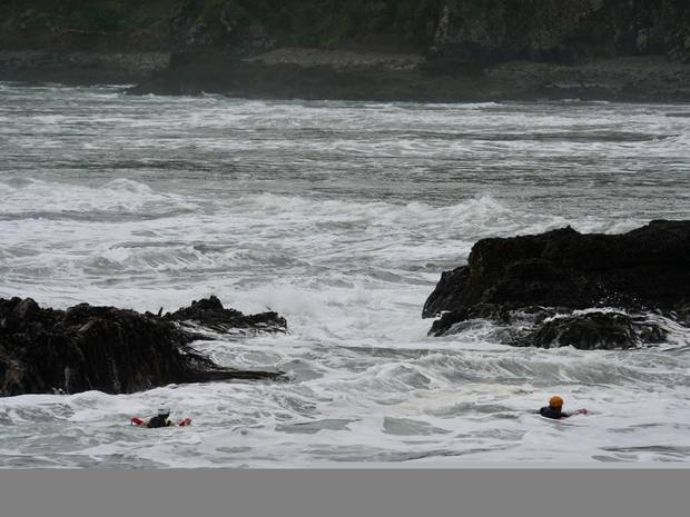 Surf lifesaving crews in the water searching around rocks for any sign of the missing man today. Photo / SLNZ