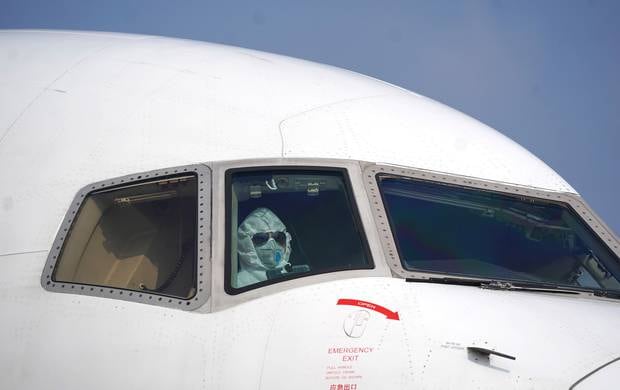 A pilot wearing a protective suit parks a cargo plane at Wuhan Tianhe International Airport in China's Hubei Province. Flight crew flying Kiwis from China will have protective equipment. Photo / AP