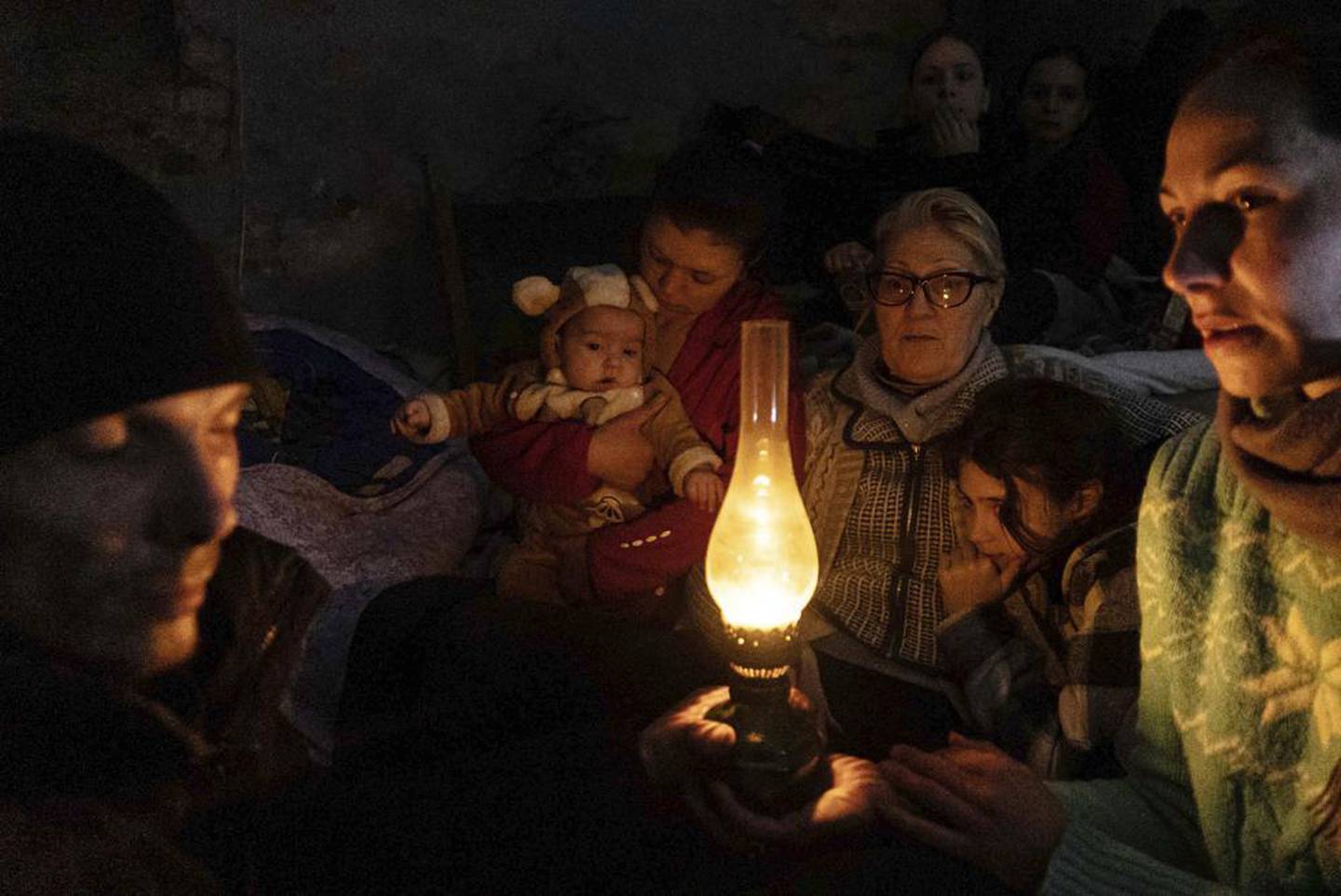 2022 年 3 月 6 日，星期日，乌克兰马里乌波尔的一个防空洞里，人们围坐在一盏灯旁。照片/美联社