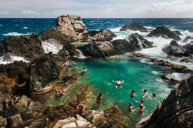 Tourists swimming in a protected pool, sheltered from the rough North coast of Aruba. Photo / Getty Images