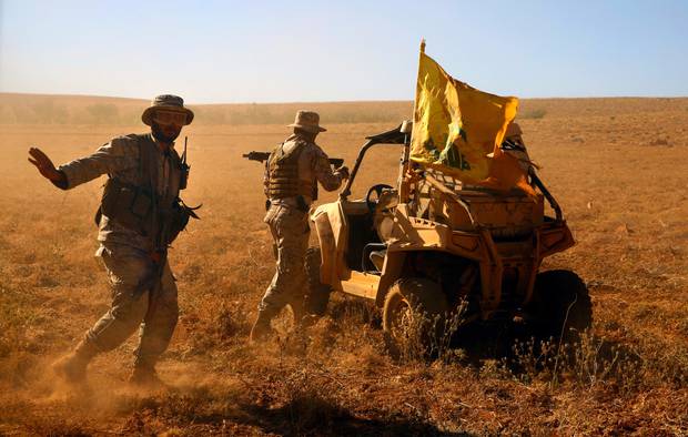 Hezbollah fighters stand near a four-wheel vehicle positioned at the site where clashes erupted between Hezbollah and al-Qaida-linked fighters. Photo / AP