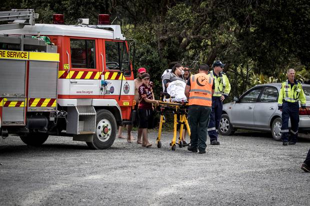 The woman who tried to save the boy is helped to a waiting ambulance by paramedics. Photo / Michael Craig