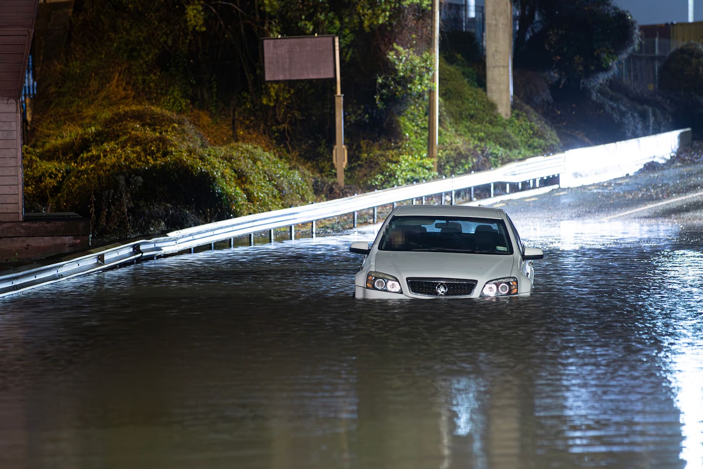 A man climbed out of his car window after becoming trapped by floodwaters on Onehunga Harbour Road, Onehunga, early on Saturday morning. Photo / Hayden Woodward