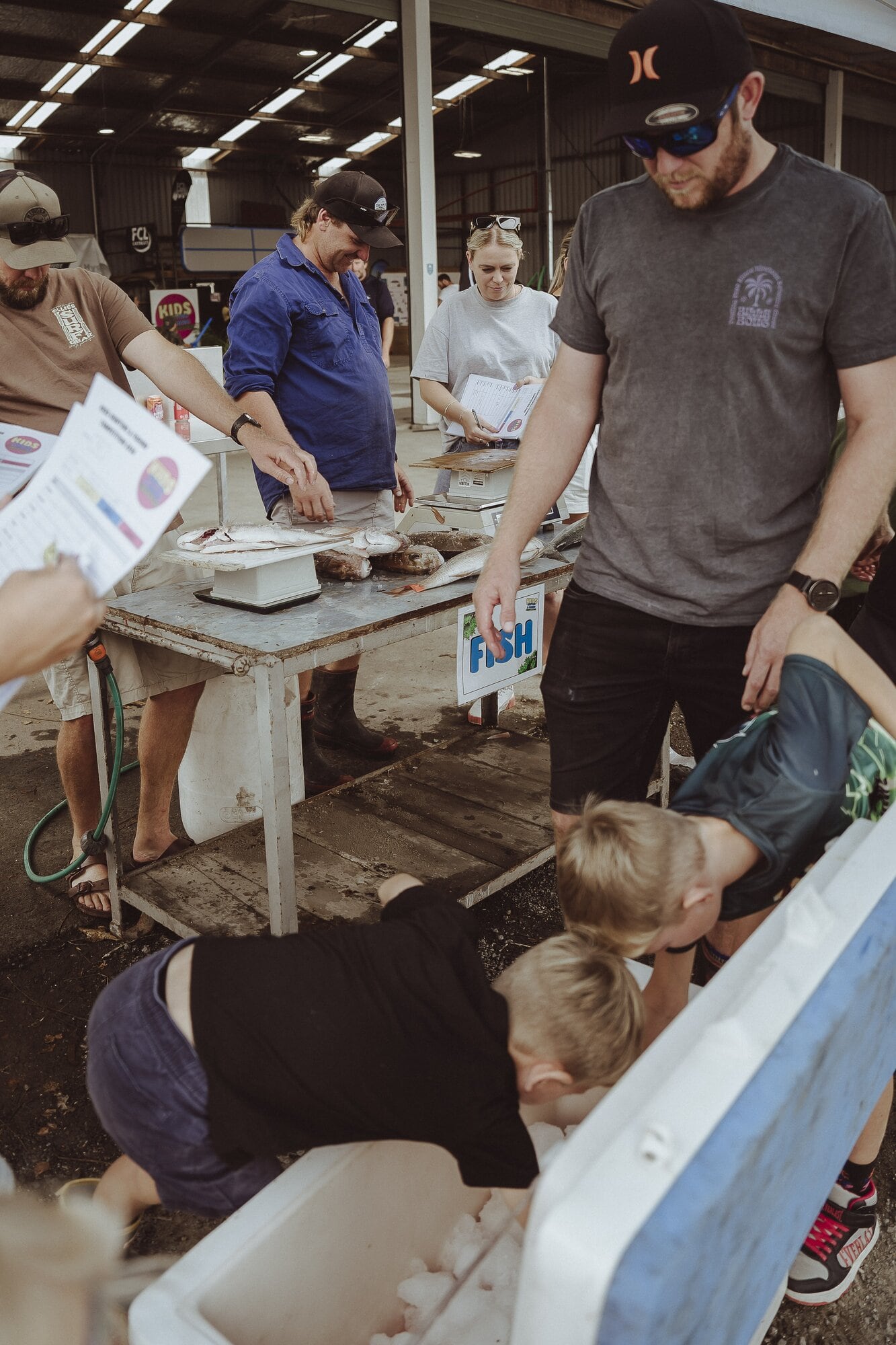 The Connelly brothers dig deep in their chilli bin to enter their catches while father Tristan Connelly looks on. Photo / Jamie Smith / The Light Alchemist