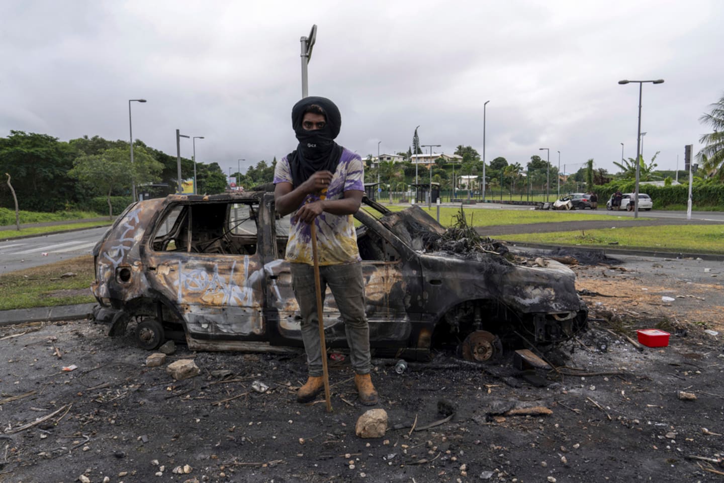 A man stands in front of a burnt car after unrest in Noumea, New Caledonia. Photo / AP