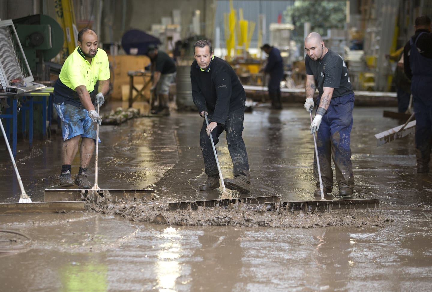 Workers scraping mud from the floor at Ullrich Aluminium in Cornish Street, Petone in May 2016. Photo / Mark MItchell