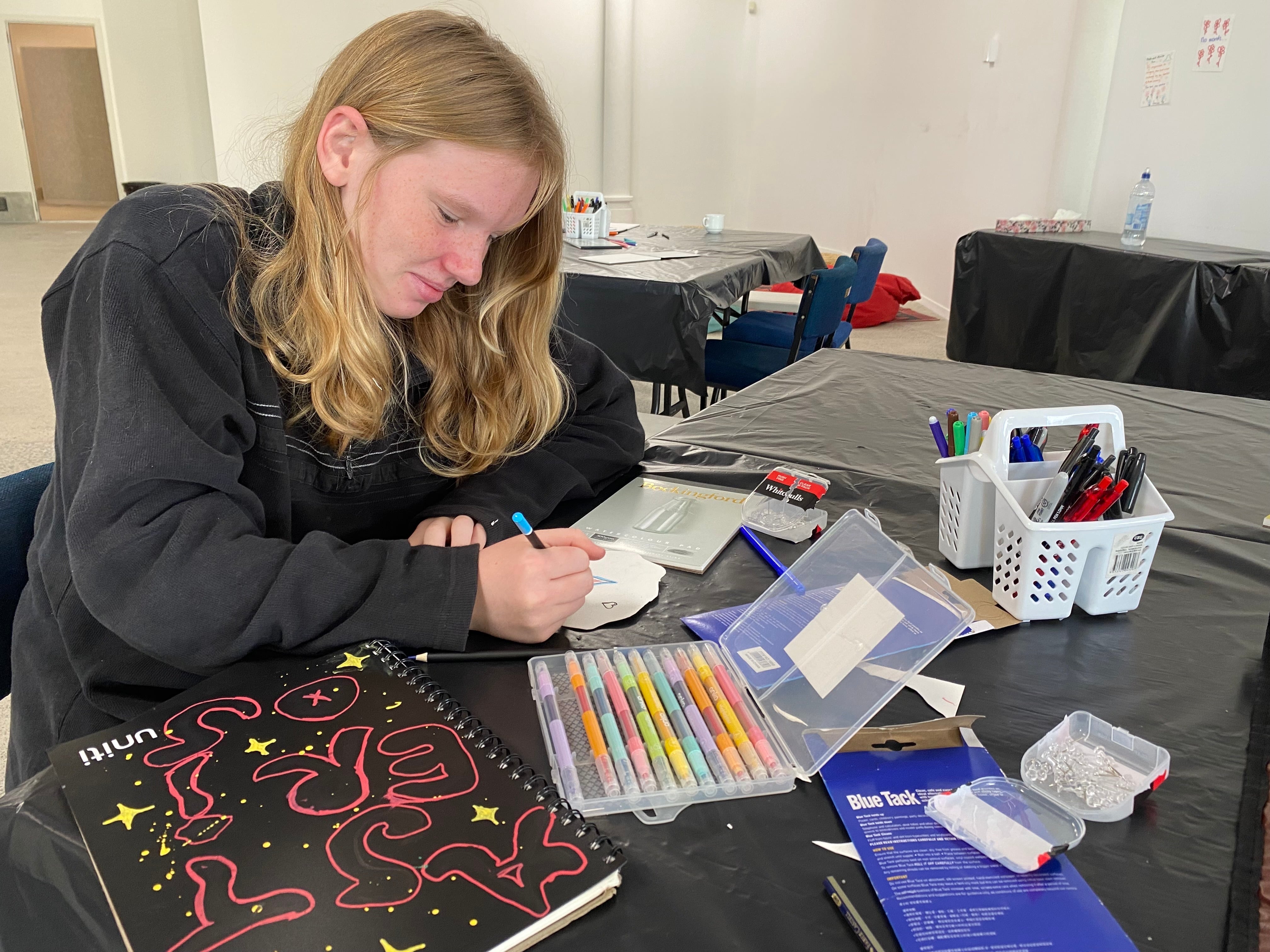 Hema Veale, age 13, drawing a flower to place on the commemoration wall at the centre at Mount Maunganui. Photo / Rosalie Liddle Crawford