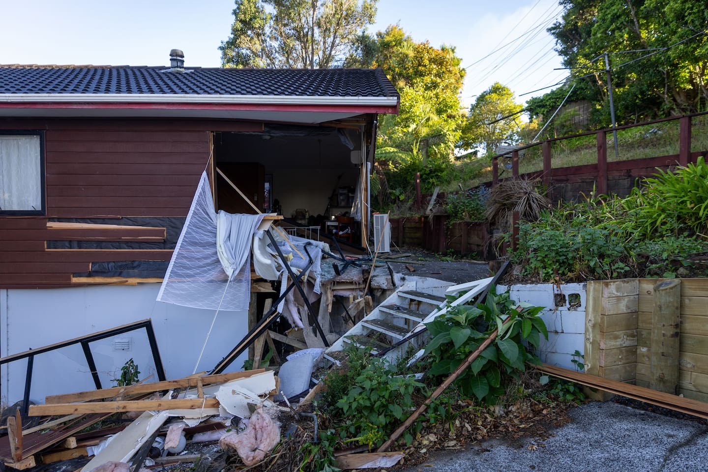 A manhunt is under way for a driver who crashed into two houses on Don Buck Rd in Massey, West Auckland, before fleeing on foot on Thursday morning. Photo / Michael Craig