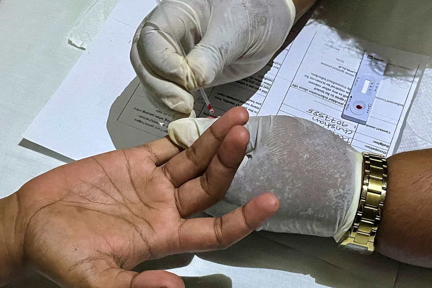 A staff member conducts a blood test at a Medical Services Pacific mobile clinic. Photo / STR, AFP