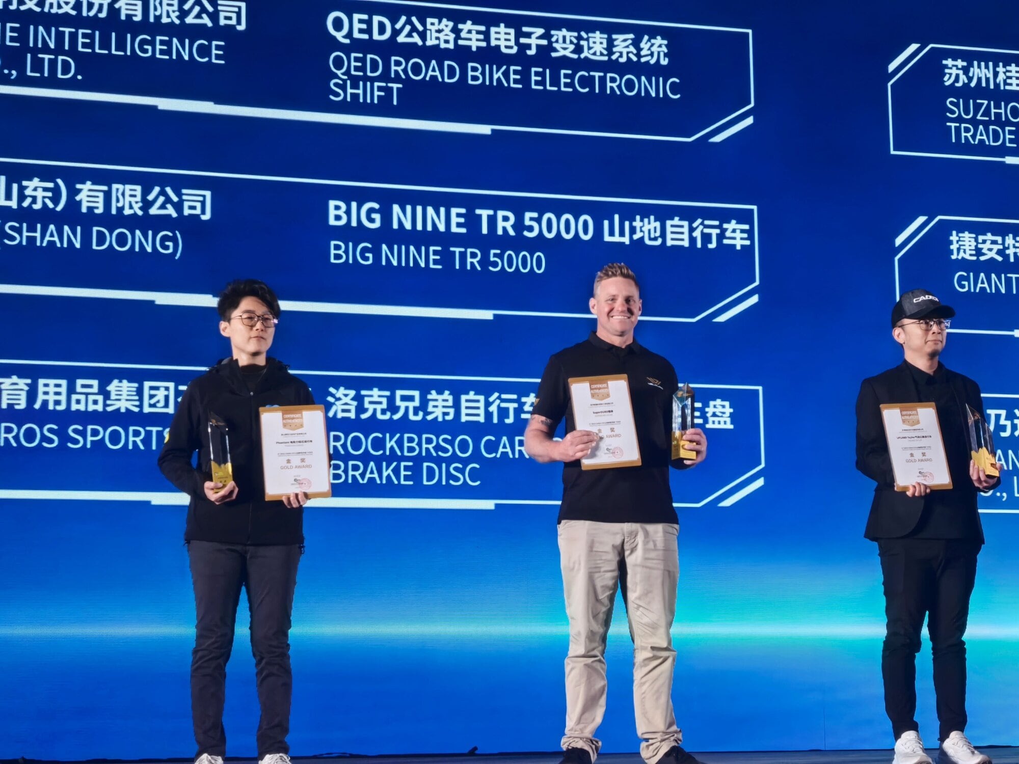 Dan Wallace on stage at China Cycle 2025 after Velduro won gold at the opening ceremony.