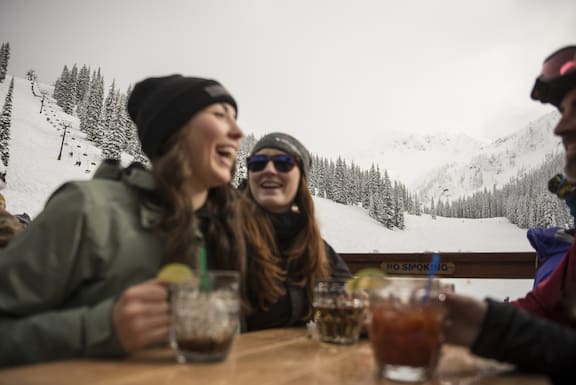 Friends connect over drinks with snowy slopes as the backdrop. Photo / Destination British Columbia