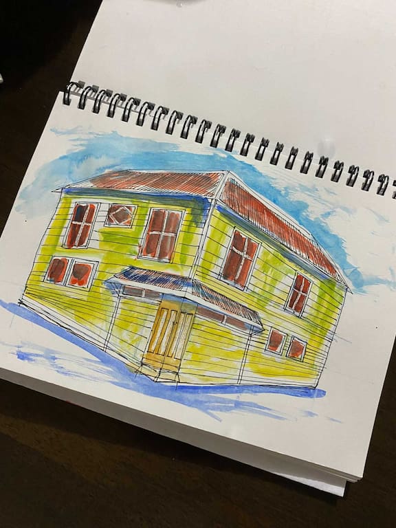 A person sketching a construction site scene in a notebook.