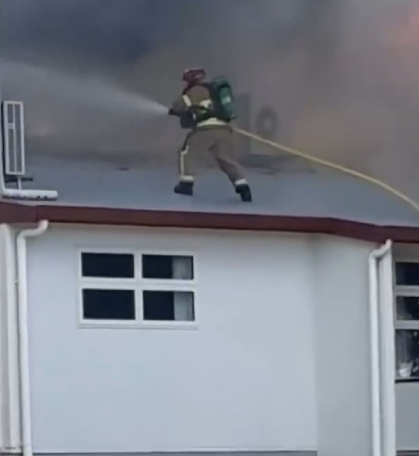 A firefighter climbed onto the roof of Taupo Nui a Tia College to battle the blaze which has broken out this afternoon.