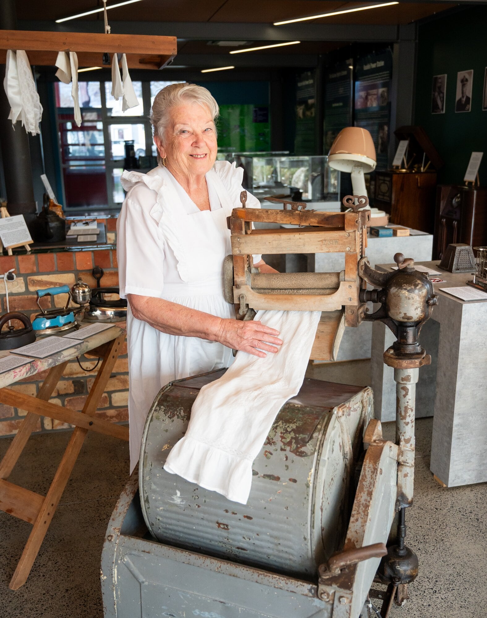  From another time – Western Bay Museum volunteer Jenny Gawith gets in the spirit with the circa 1915 oscillating washing machine. Photo / Brydie Thompson
