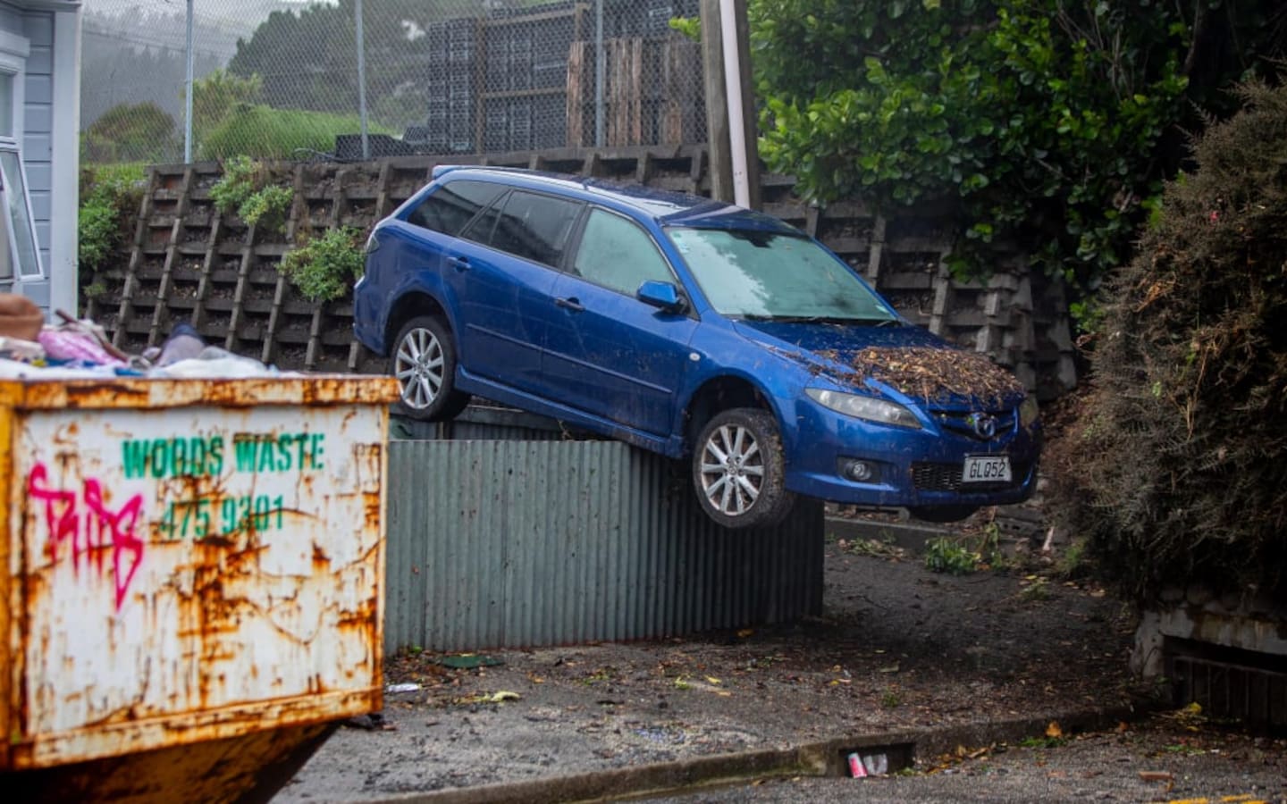 A car carried by floodwaters landed on top of a chest-high fence after Monday's torrential rain in Wellington. Photo / RNZ, Mark Papalii