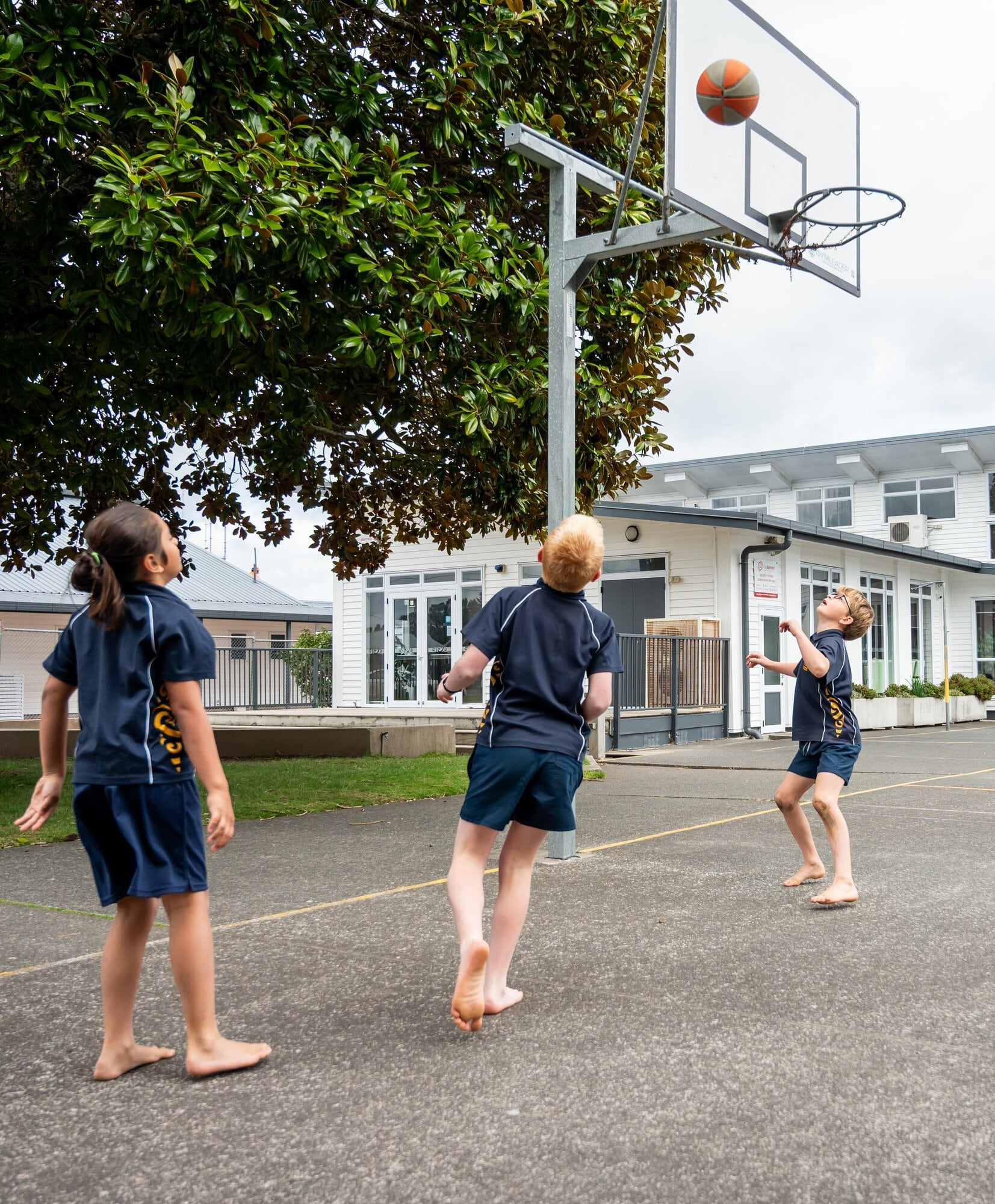 Louis Te Wheoro, 8, Flynn Bart, 9, and Mason Edkins, 9, enjoy one of their last chances to play basketball on the top sports court before it's resurfaced. Photo / Brydie Thompson