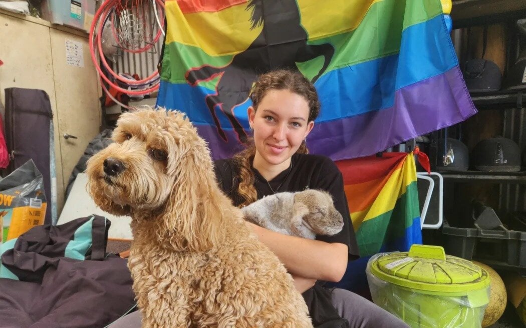 Radha Foulds, one of the coaches, cradles a newborn lamb, with Awhi on guard. Photo / RNZ, Sally Round