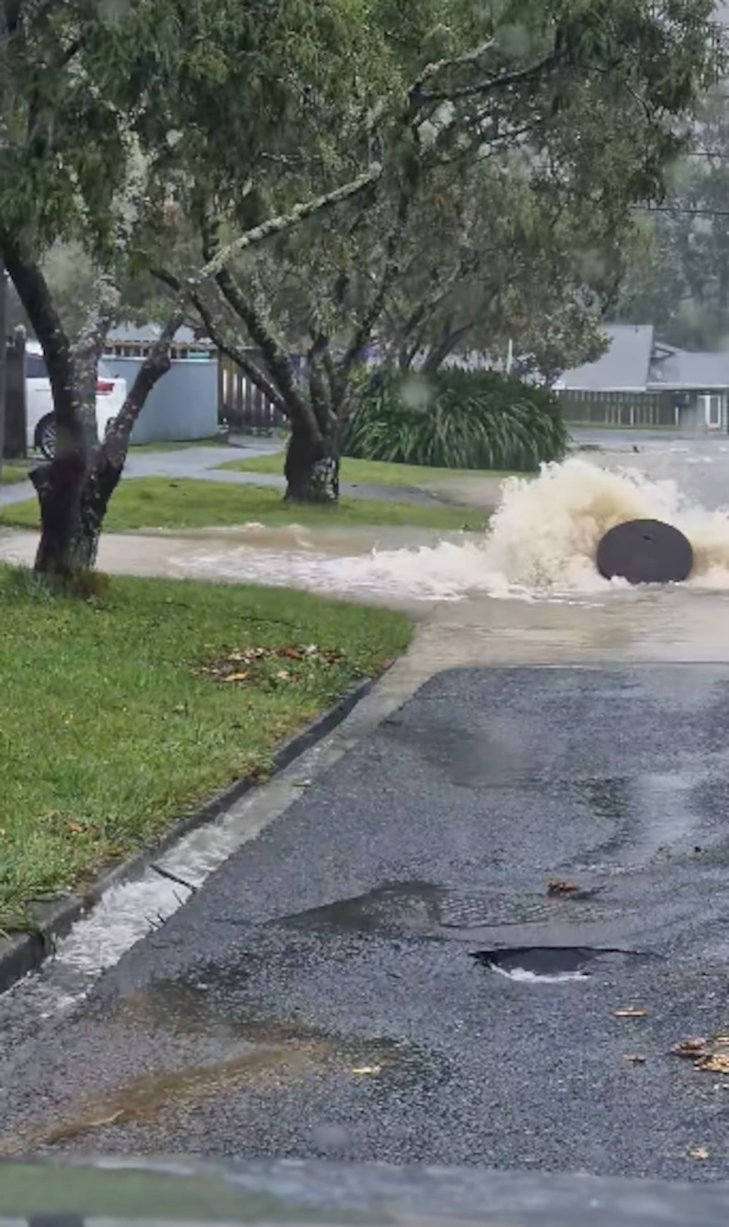 Flooding on Kamahi St, Stokes Valley, forced up a manhole cover and broke holes in the surface of the road.