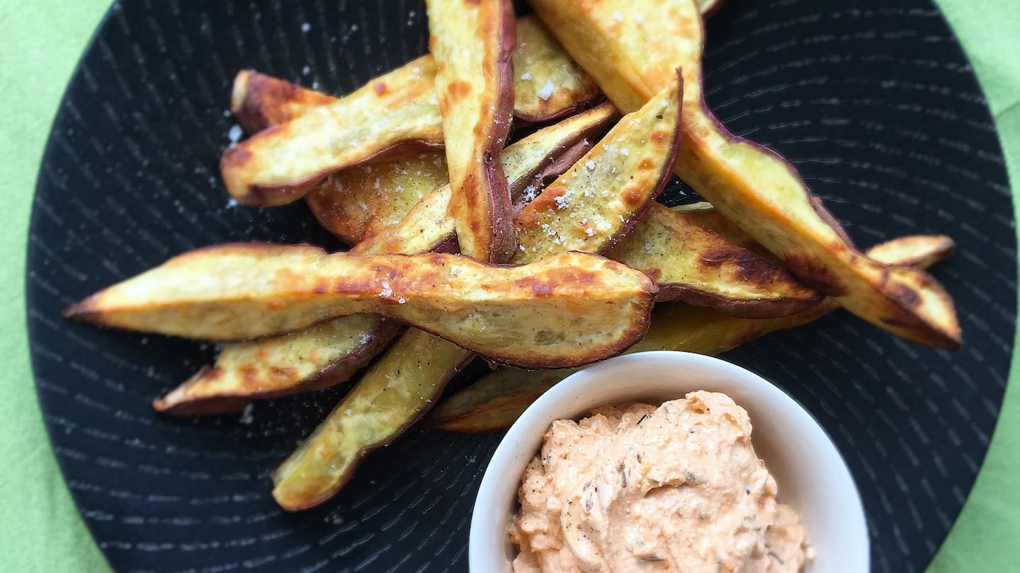 A close-up shot of a plate of kumara fries with a dipping sauce.