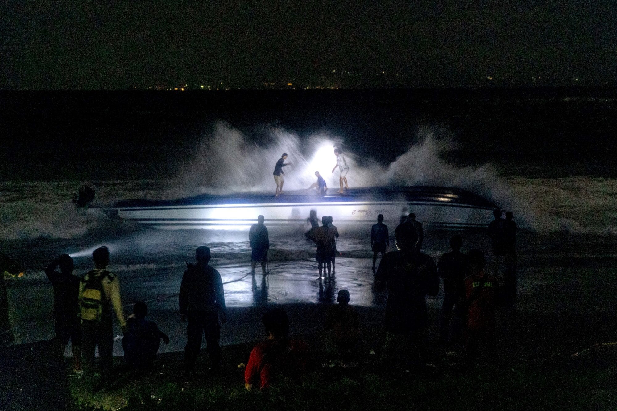 250806) -- BEIJING, Aug. 6, 2025 (Xinhua) -- People stand near the fast boat after it capsized at Sanur beach in Bali, Indonesia, Aug. 5, 2025. The Chinese consulate general in Denpasar, Bali, Indonesia, confirmed on Tuesday that two Chinese nationals were killed in a fast boat capsizing accident off Indonesia's Bali Island earlier in the day. (Photo by Dicky Bisinglasi/Xinhua) (Photo by Dicky Bisinglasi / XINHUA / Xinhua via AFP)