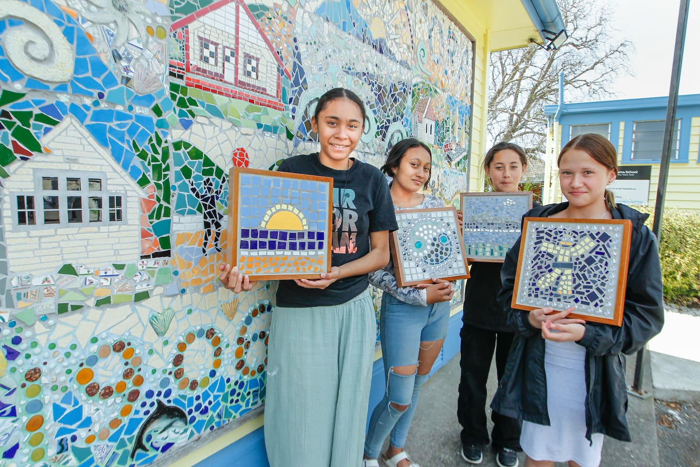 Merena Tahat-Timas (left), Anika Tapiata-Harmer, Horiana Tahau and Georgia Epere with their mosaics in front of a mosaic commemorating 100 years of Waimārama School, funded through Creative in Schools. Photo / Warren Buckland
