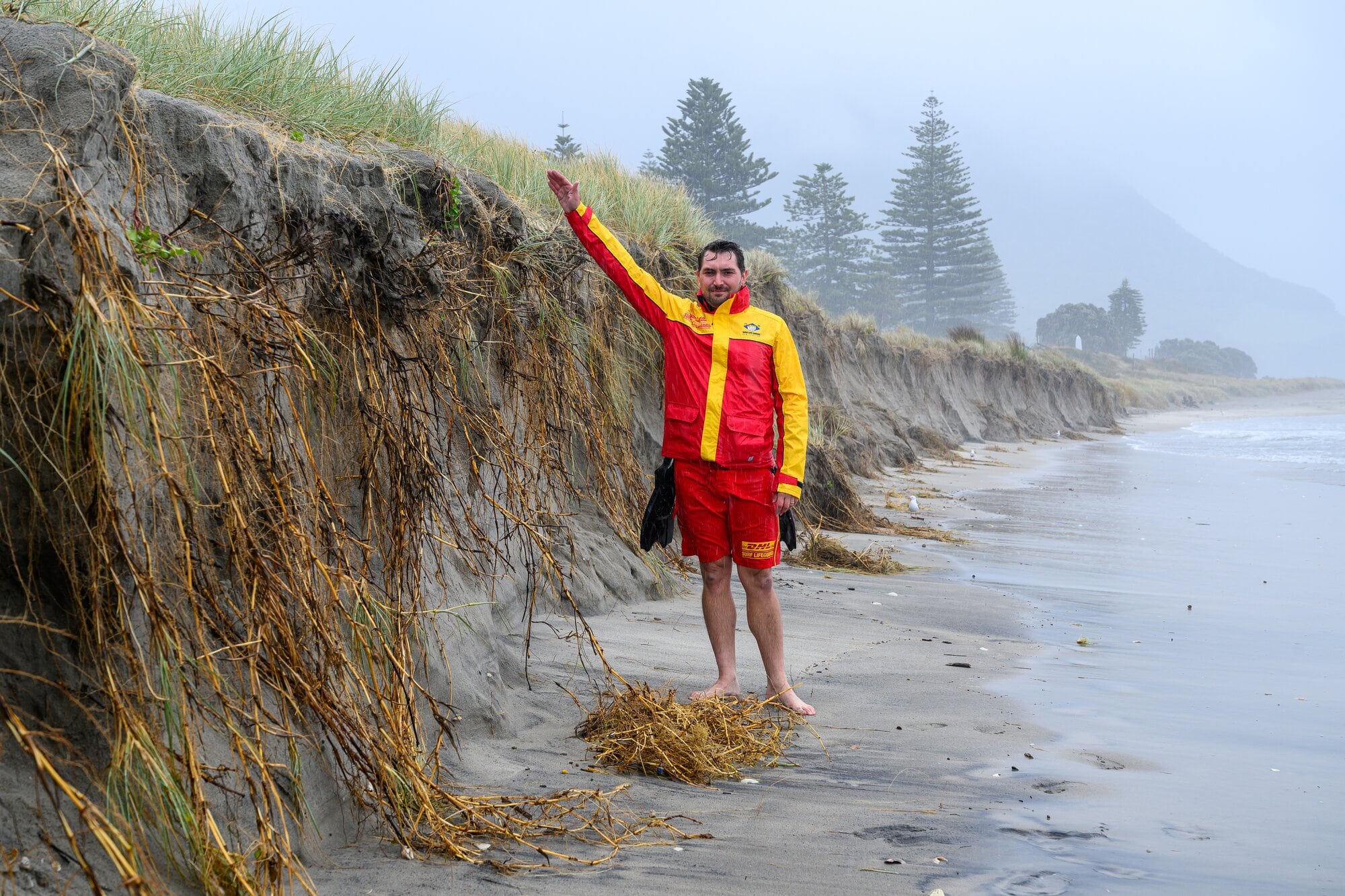  Surf Life Saving New Zealand Eastern Region manager Chaz Gibbons-Campbell demonstrating the height of the drop-off from the sand dune to the beach near Banks Ave, Mount Maunganui.  Photo / David Hall