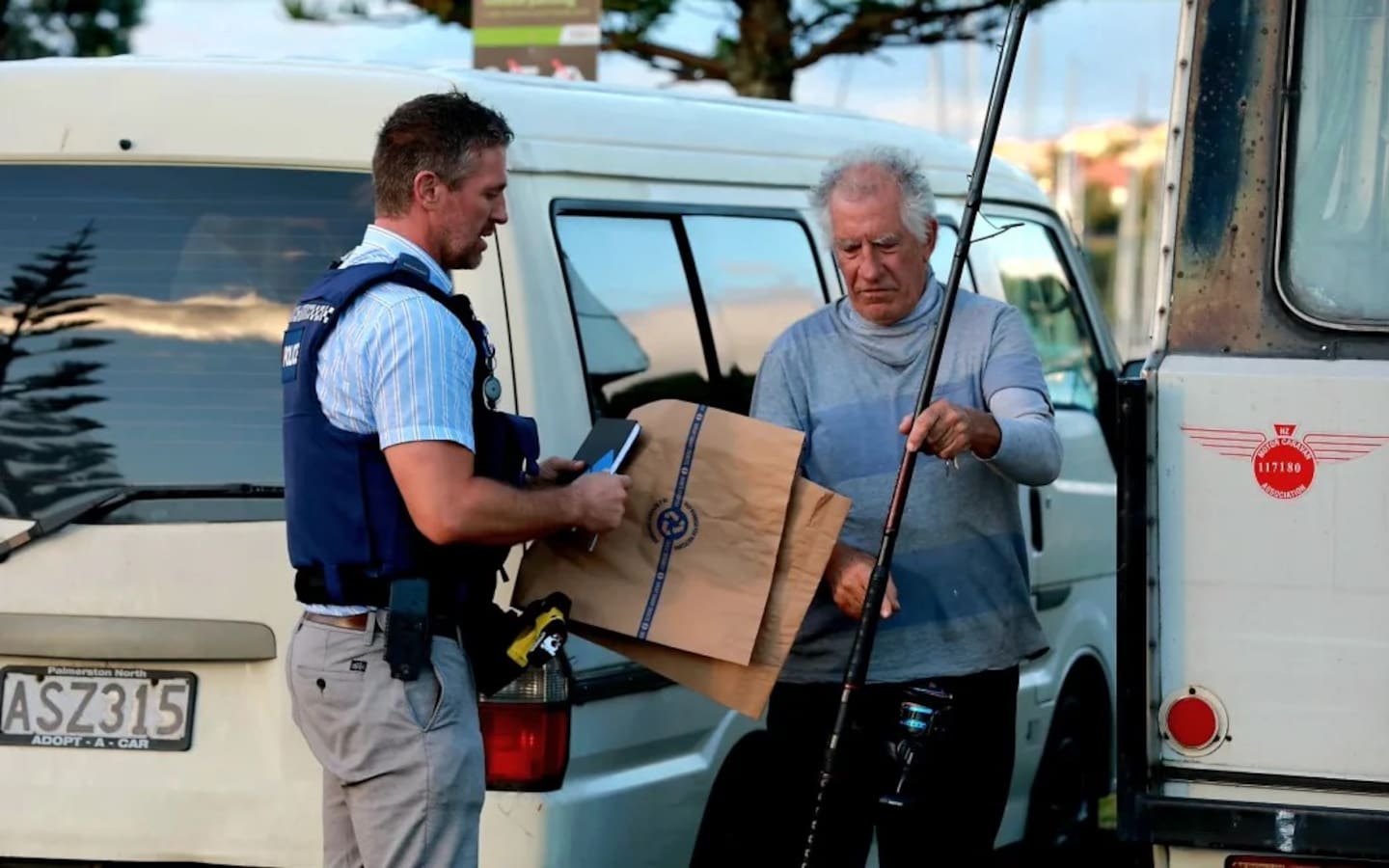 渔民保罗·米德尔顿在海湾港打捞出包裹着塑料袋的遗体后与警方交谈。 照片/RNZ/尼克·蒙罗